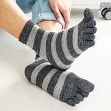 Load image into Gallery viewer, Gray and white striped socks worn by a person sitting on a white surface.
