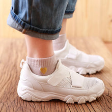Load image into Gallery viewer, White sneakers worn with rolled-up jeans on a wooden floor