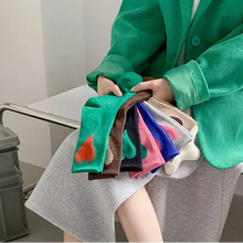 Load image into Gallery viewer, Person holding colorful socks with a green jacket and gray pants in an indoor setting.
