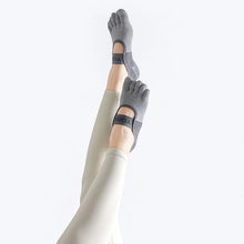 Load image into Gallery viewer, Gray yoga socks with a brand logo worn by a person on a white background