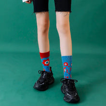 Load image into Gallery viewer, Person wearing black shorts and colorful socks on a green background
