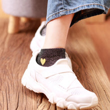 Load image into Gallery viewer, White sneaker with a heart-shaped gold detail on a wooden floor
