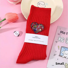 Load image into Gallery viewer, Red sock with a decorative heart on a pink background
